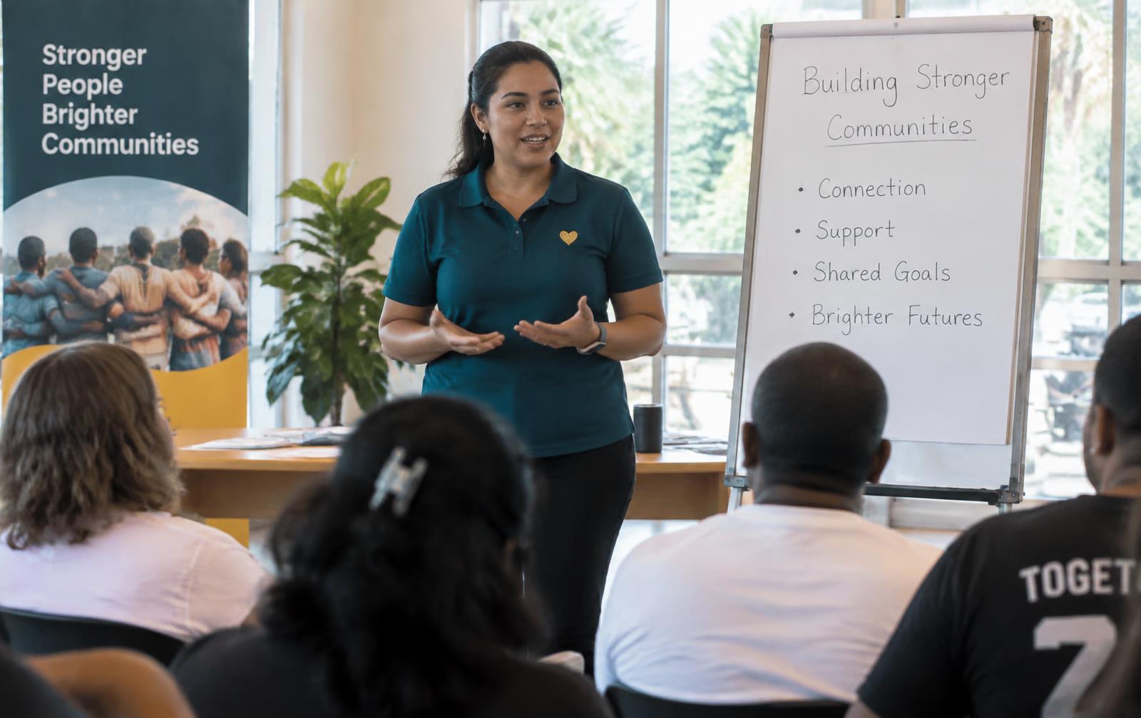 A Madrid Foundation facilitator in a branded teal shirt leading a community seminar